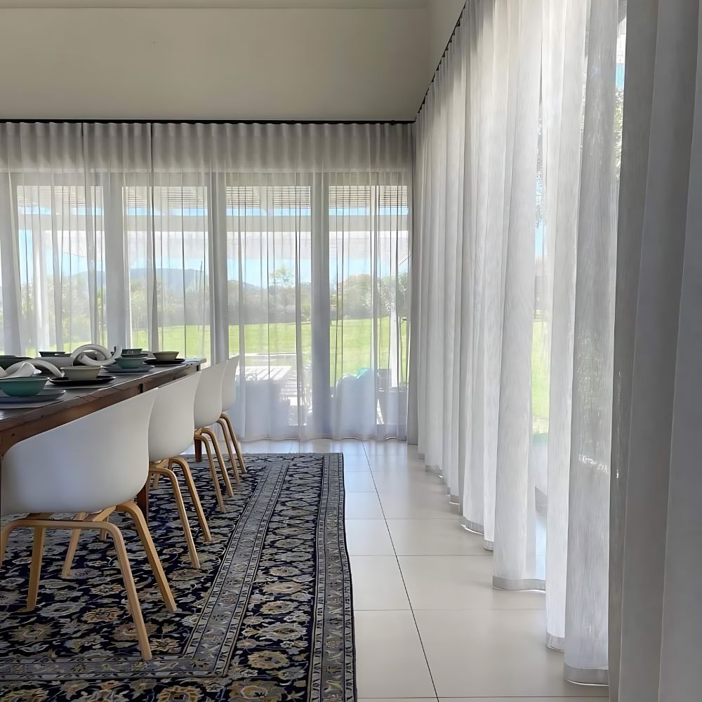 Floor-length sheer curtains beside a dining area